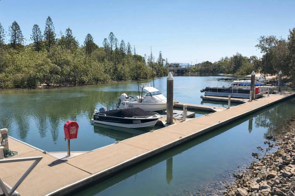 Private marina on river with moored boats, timber dock and mature riverside trees