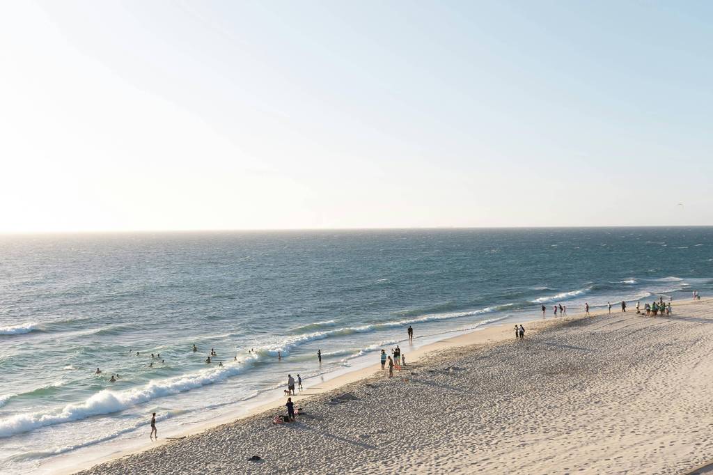 Beach with swimmers and waders along shoreline with breaking waves