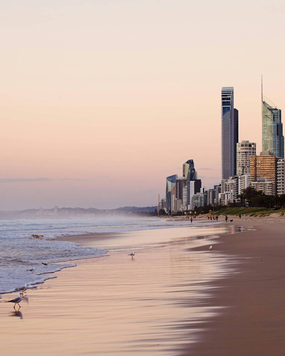 Wide stretch of Gold Coast sand with morning surfers in the water