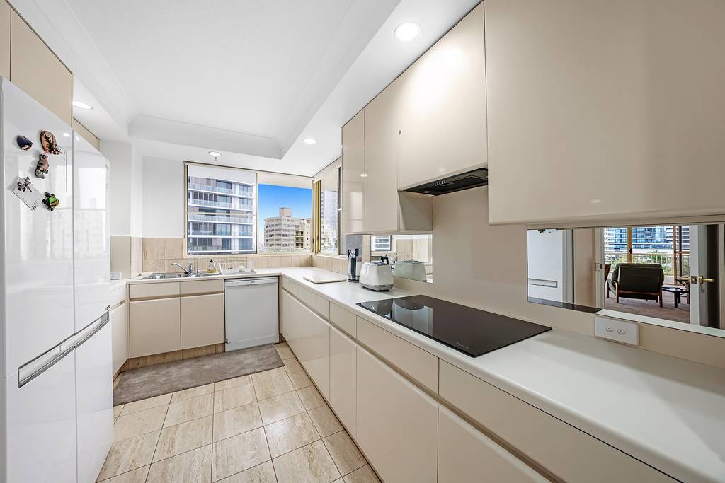 Apartment kitchen with refrigerator, dishwasher, stovetop and corner windows