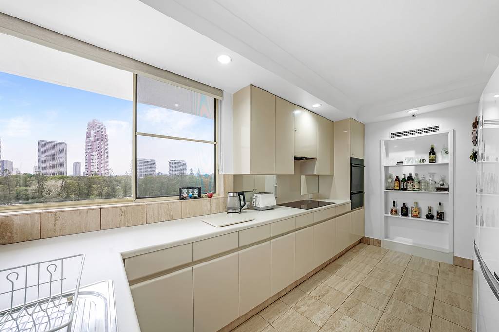 Apartment kitchen with broad windows, tiled splashback and drinks shelving