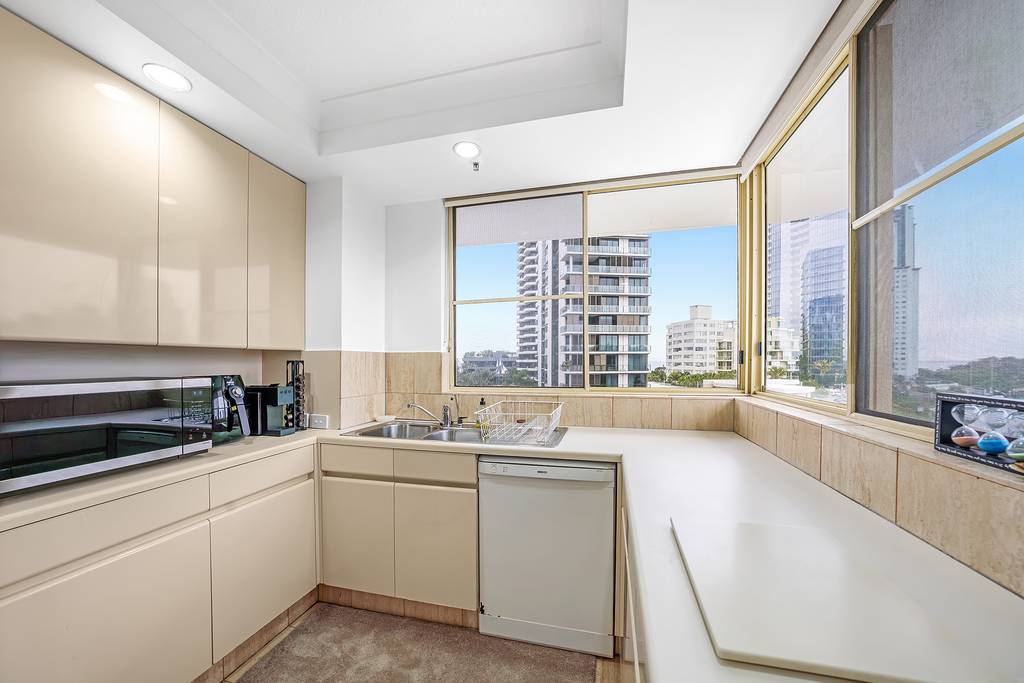 Kitchen dishwasher, sink and corner bench beside large windows