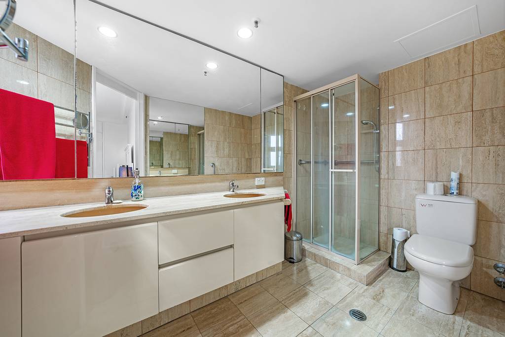 Bathroom with double vanity, mirrored wall, shower and toilet