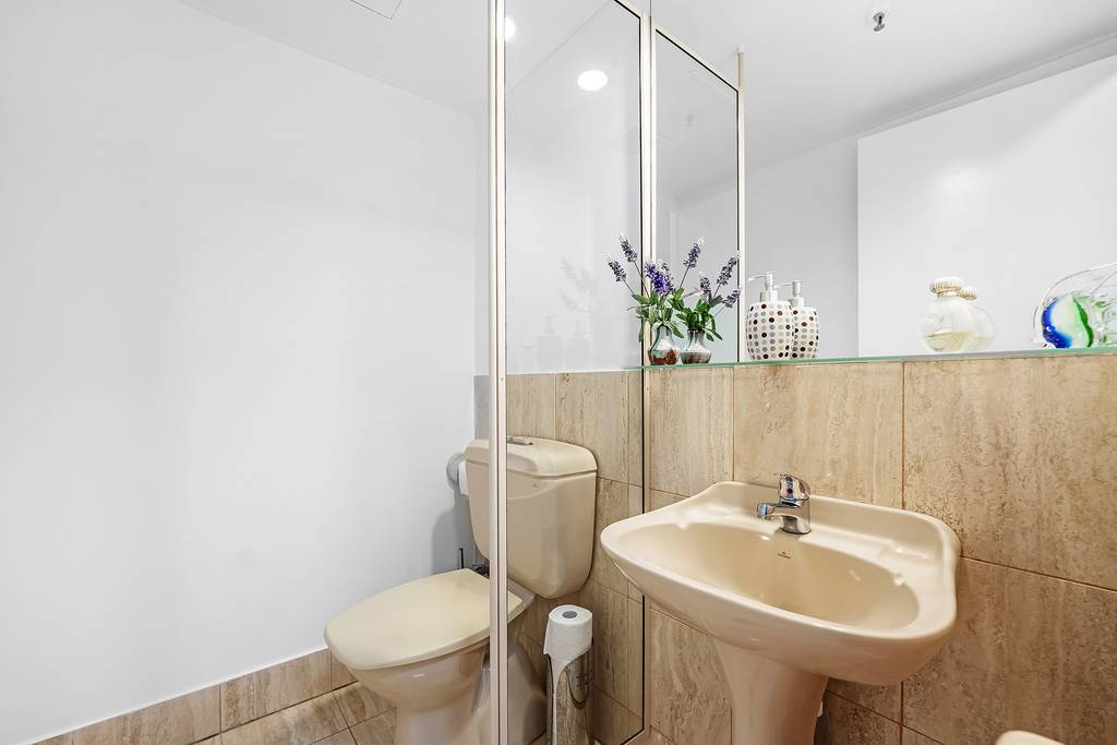 Separate toilet with tiled walls, basin and mirrored cabinet