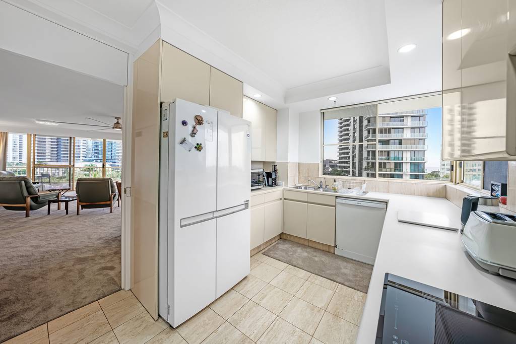 Kitchen with refrigerator, dishwasher, toaster and living room beyond